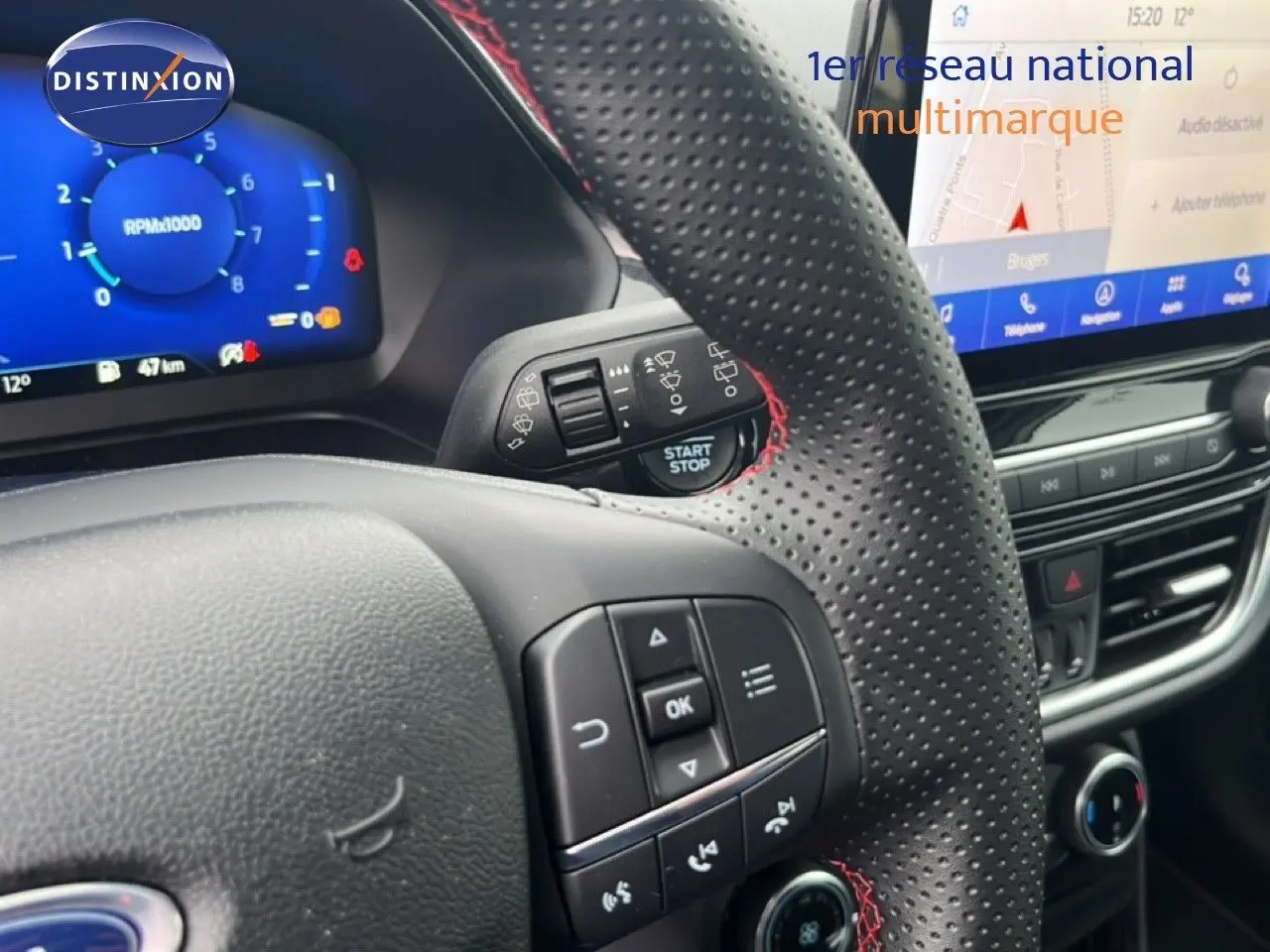 Vue rapprochée du volant perforé avec surpiqûres rouges et tableau de bord numérique du Ford Puma gris magnétique 2024.