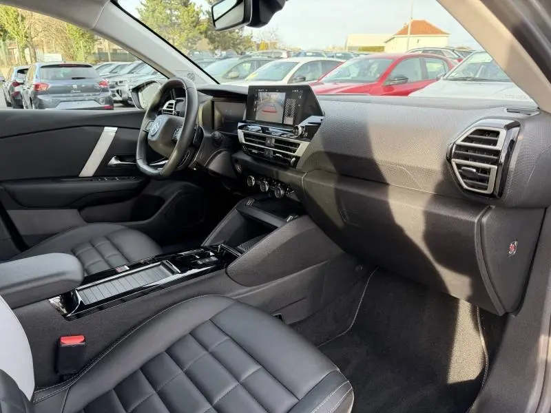 Vue intérieure côté passager du Citroën C4 X 2025, avec tableau de bord moderne et sièges en cuir noir.