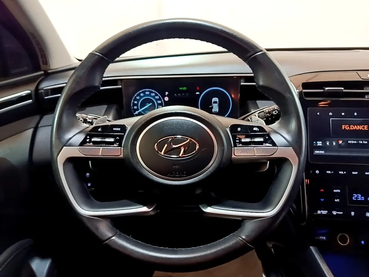 Vue intérieure centrée sur le volant cuir noir du Hyundai Tucson 2022 avec tableau de bord digital et écran tactile.