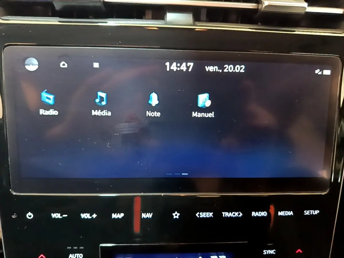 Écran tactile central affichant menu radio, média, note et manuel dans Hyundai Tucson gris foncé, vue intérieure frontale.