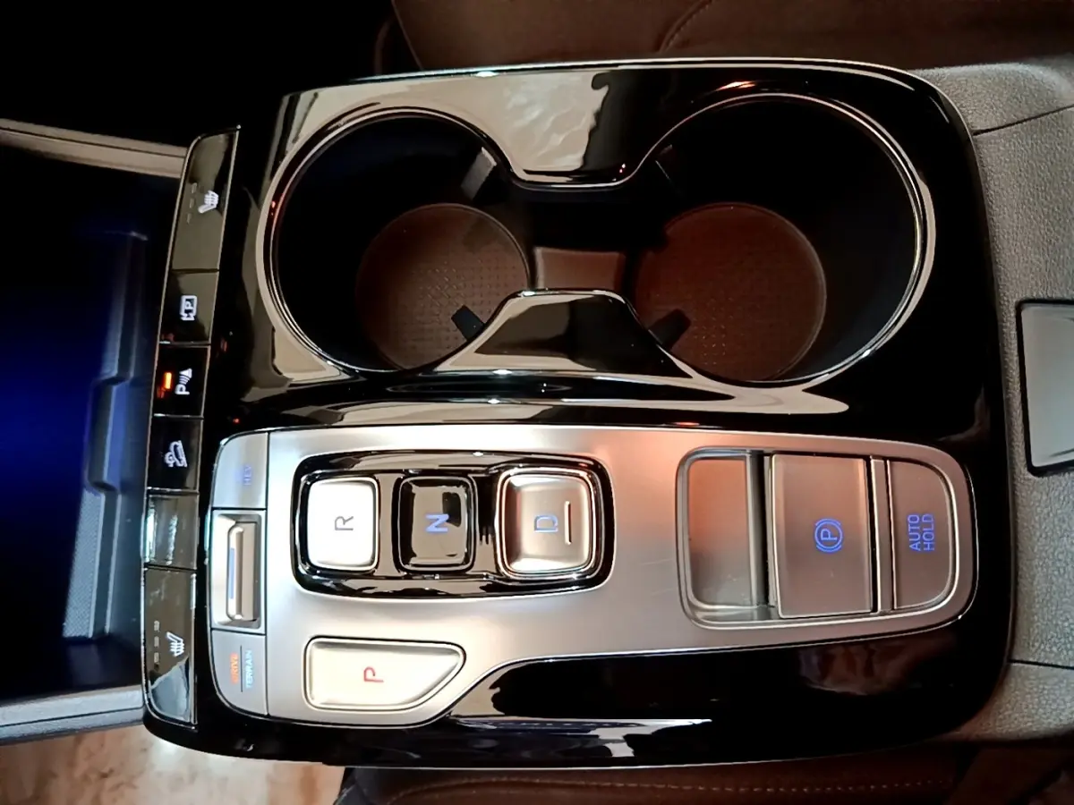 Vue plongeante sur la console centrale noire du Hyundai Tucson 1.6 PHEV 265 HTRAC avec commandes de boîte auto et porte-gobelets.