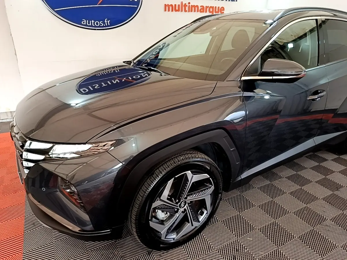 Vue 3/4 avant droit d'un Hyundai Tucson gris foncé avec jantes alliage au design moderne dans un showroom.
