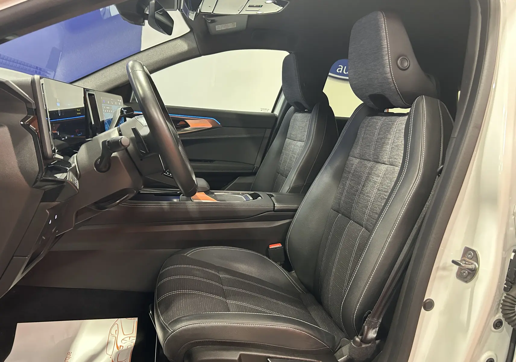Vue intérieure côté conducteur du Renault Austral blanc nacré 2024, sièges en cuir noir avec surpiqûres blanches et tableau de bord moderne.