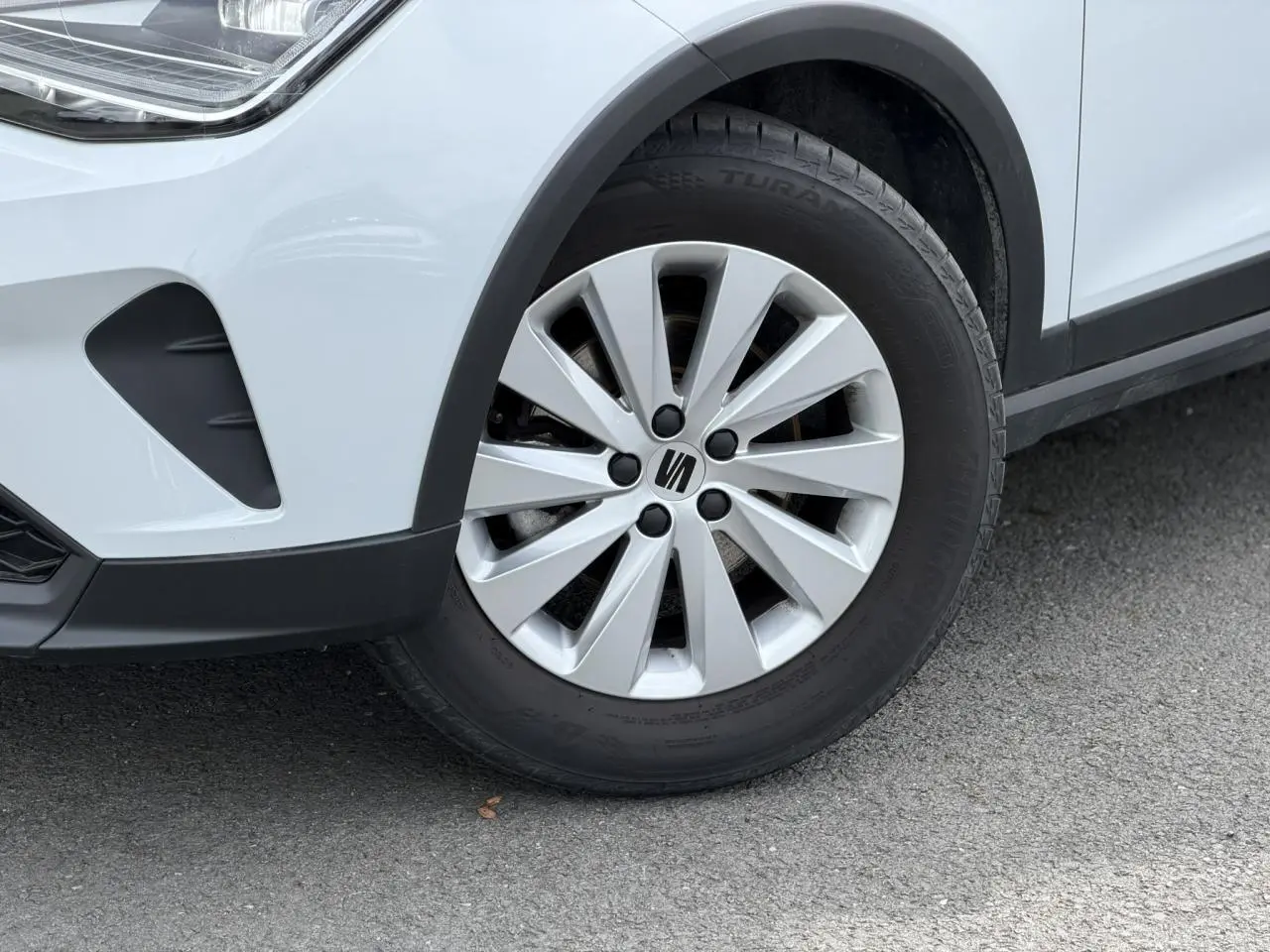 Gros plan sur la roue avant droite d’un SEAT Arona blanc alpin avec jante alliage 16 pouces design.