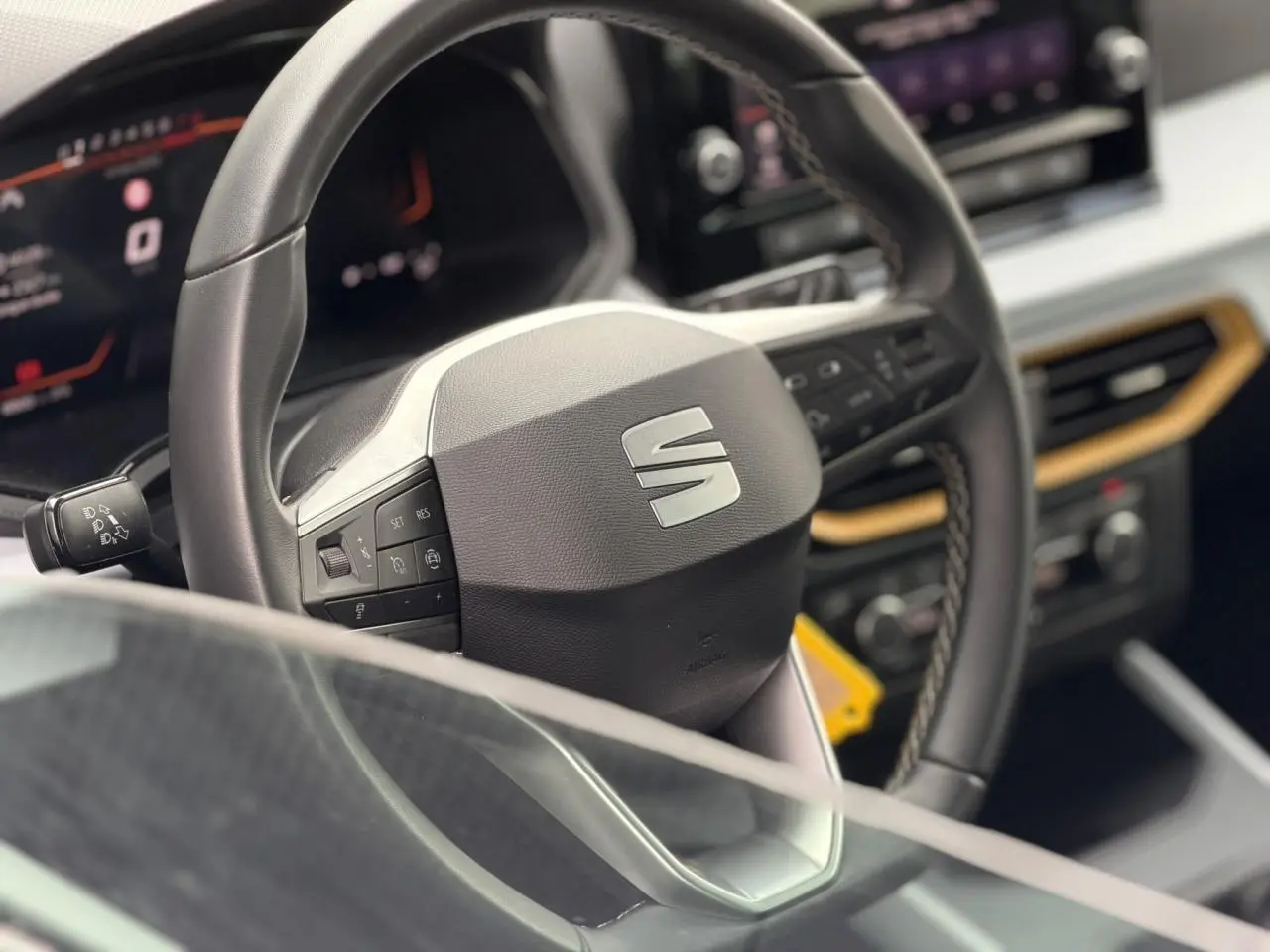 Vue rapprochée du volant noir avec logo SEAT et tableau de bord digital du SUV SEAT Arona 2025.