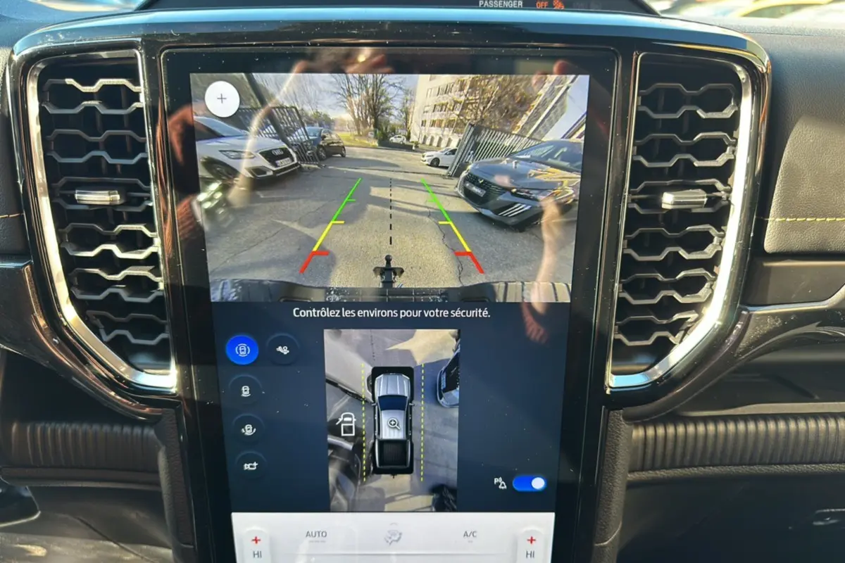 Vue intérieure du tableau de bord du Ford Ranger 2025 avec écran tactile affichant la caméra de recul et l'aide au stationnement.