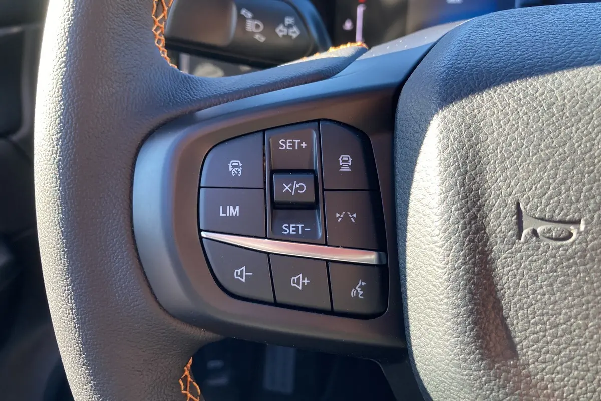 Gros plan sur les commandes au volant du Ford Ranger 2.0 205 Wildtrak Plus 2025, cuir noir avec surpiqûres orange.