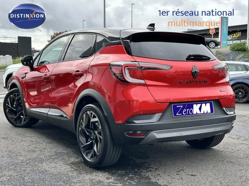 Vue 3/4 arrière droite du Renault Captur 2025 hybride en Rouge Flamme avec toit Noir Étoilé et jantes noires distinctives.