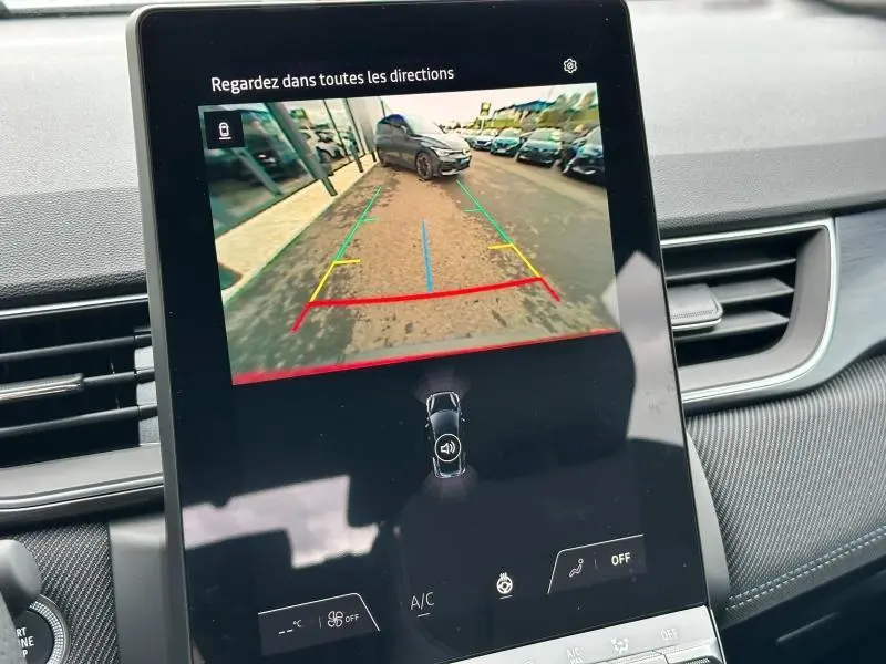 Vue de la caméra de recul affichée sur l'écran central d'un Renault Captur 2025, avec lignes de guidage colorées.