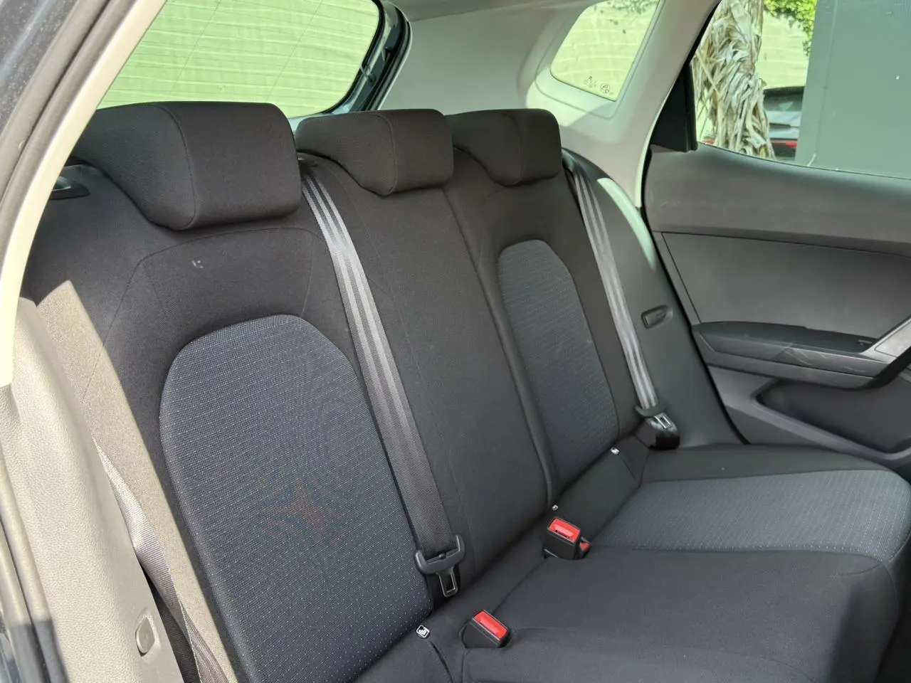 Vue intérieure côté droit montrant la banquette arrière noire du SEAT Arona TSI 115 Style 2025 avec ceintures grises.