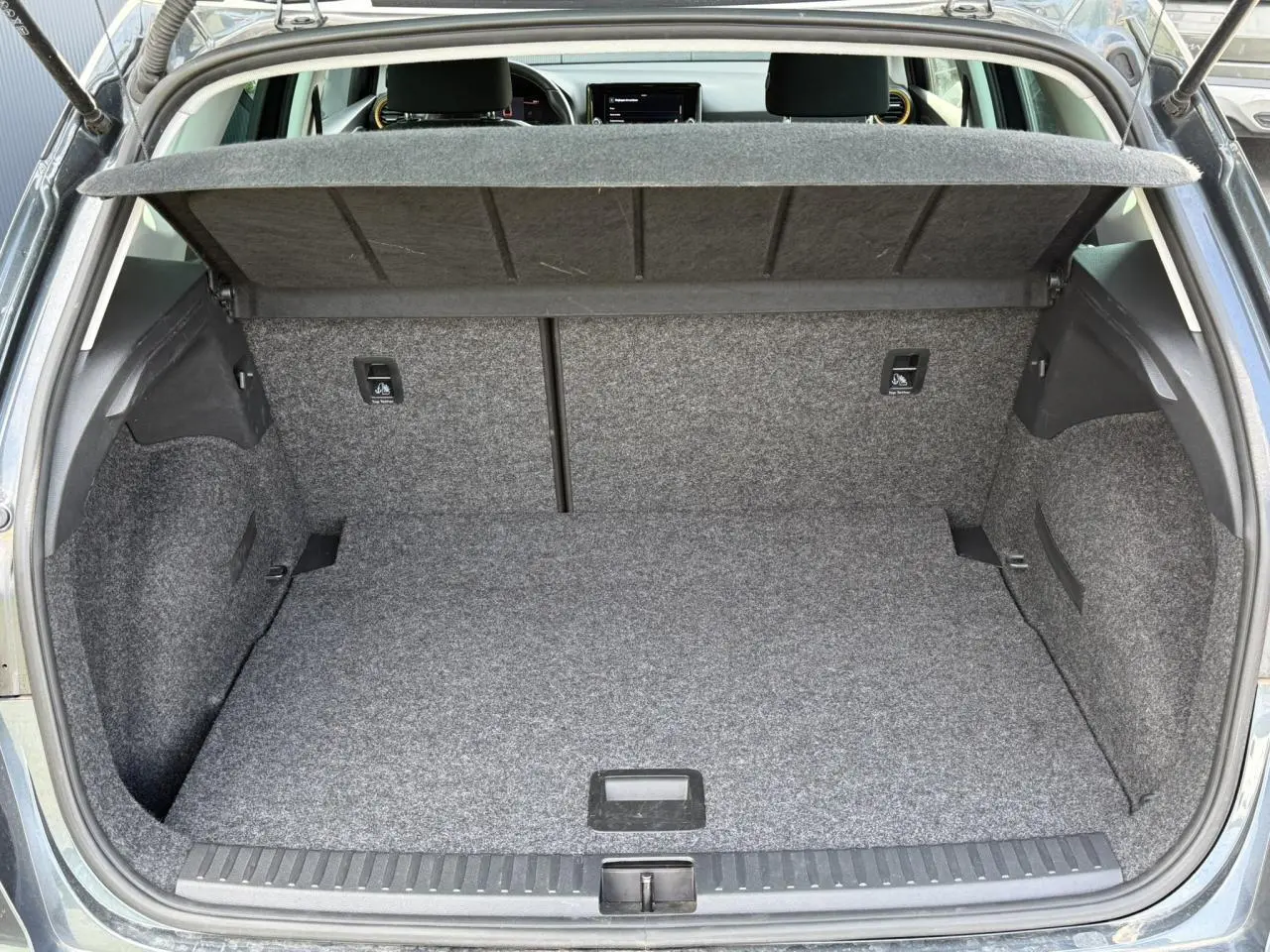 Coffre ouvert vu de l'arrière d'un SEAT Arona gris magnétique, montrant l'espace de rangement et la tablette cache-bagages.