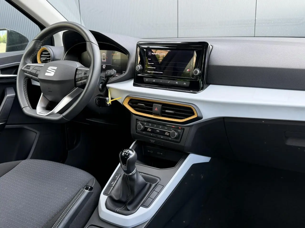 Vue intérieure côté conducteur du tableau de bord du SEAT Arona TSI 115 Style 2025 avec écran tactile et détails jaunes.