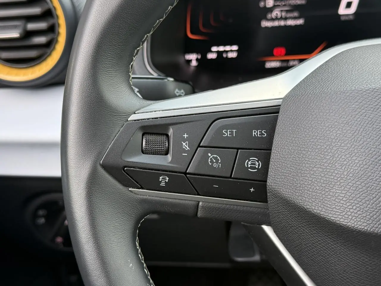Gros plan sur les commandes du volant à gauche du SEAT Arona TSI 115 Style 2025, intérieur noir avec détails argentés.