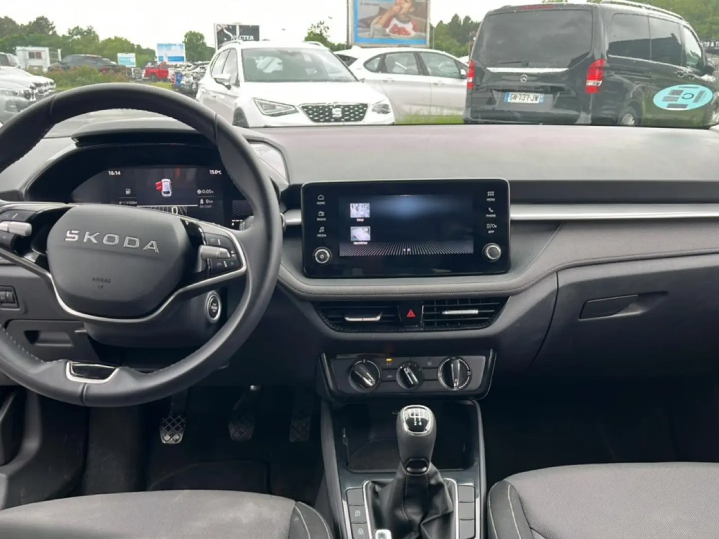 Vue intérieure frontale du tableau de bord et volant noir d'une Skoda Fabia 2025 avec écran tactile et levier de vitesse manuel.