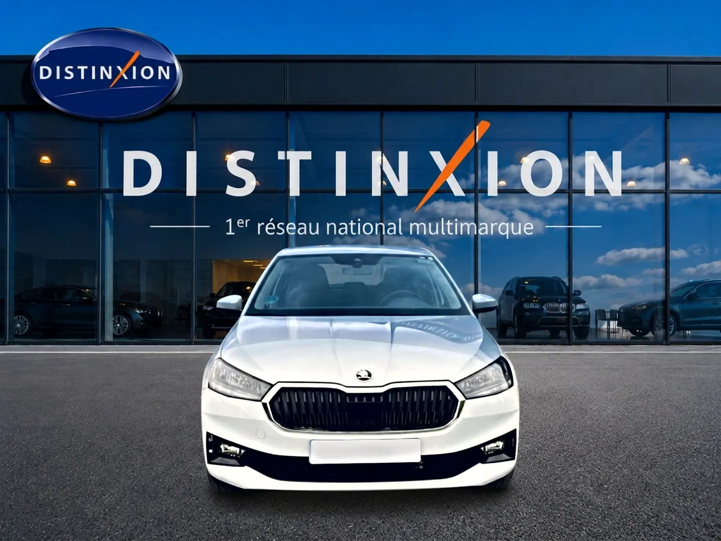 Vue avant d'une Skoda Fabia blanche 2025 avec calandre noire et phares LED devant une vitrine Distinxion.