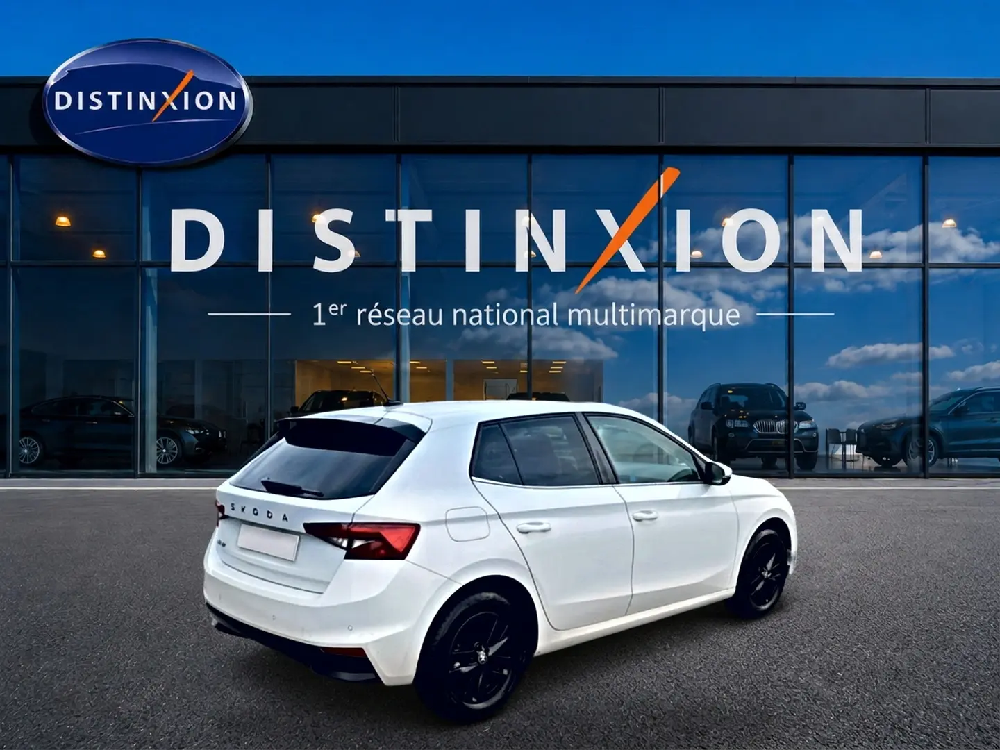 Vue 3/4 arrière droite d'une Skoda Fabia blanche 2025 avec jantes noires, stationnée devant une vitrine Distinxion.