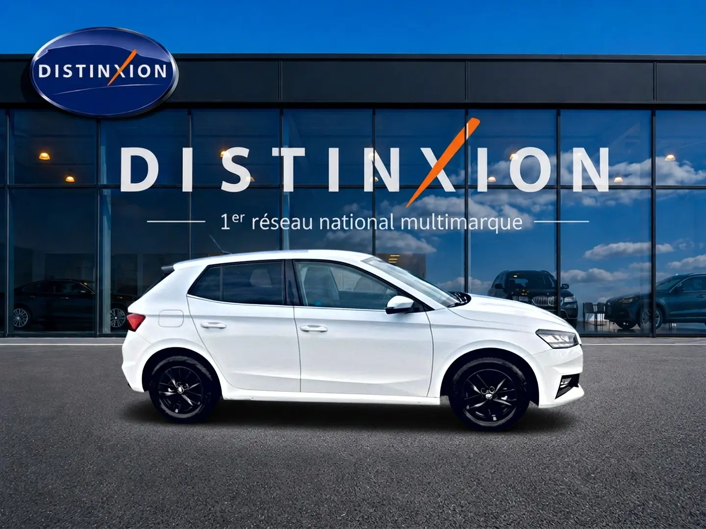 Vue de profil côté gauche d'une Skoda Fabia blanche 2025 avec jantes noires, devant une vitrine Distinxion.