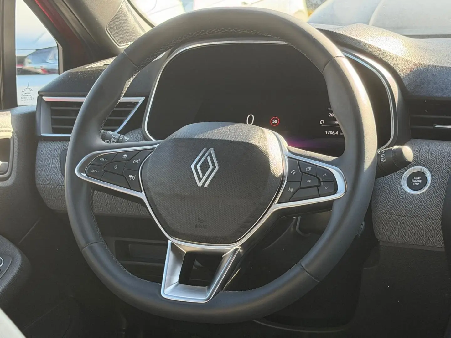 Vue rapprochée du volant multifonction noir de la Renault Clio 2025 avec bouton start/stop et tableau de bord numérique.