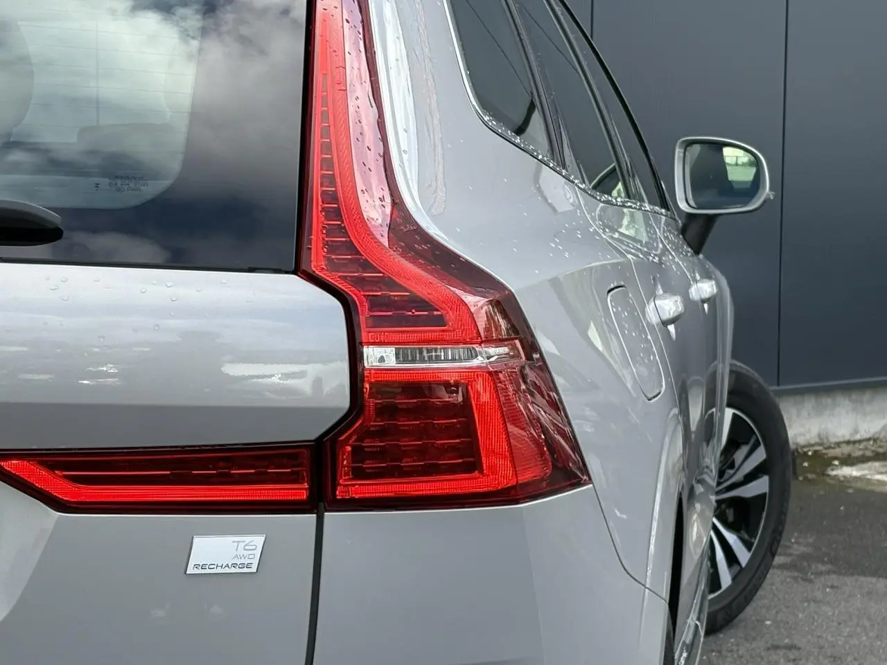 Vue 3/4 arrière droit du Volvo XC60 T6 AWD PHEV gris silver avec feux arrière LED et badge Recharge visible.