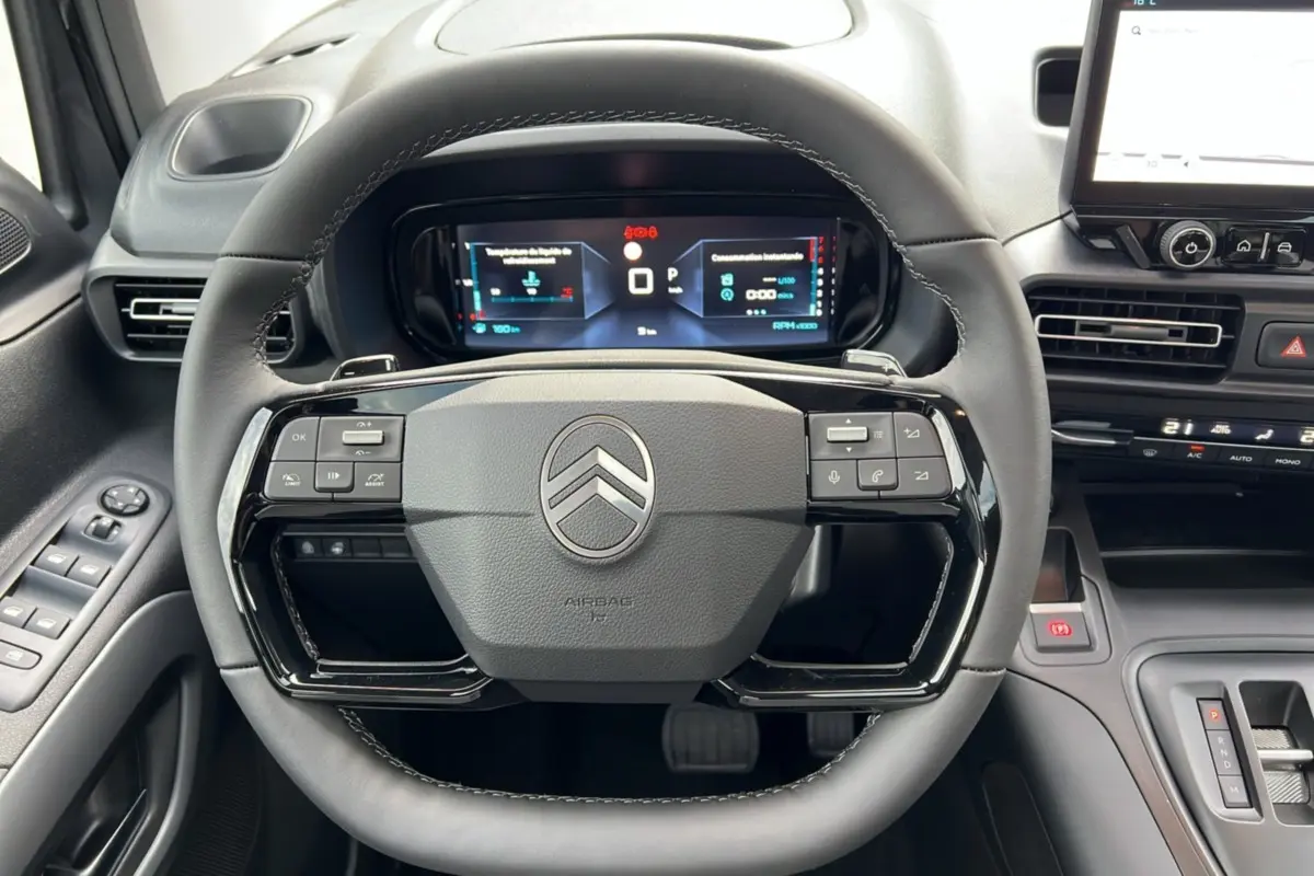 Vue intérieure centrée sur le volant noir du Citroën Berlingo 2025 avec tableau de bord numérique et commandes intégrées.