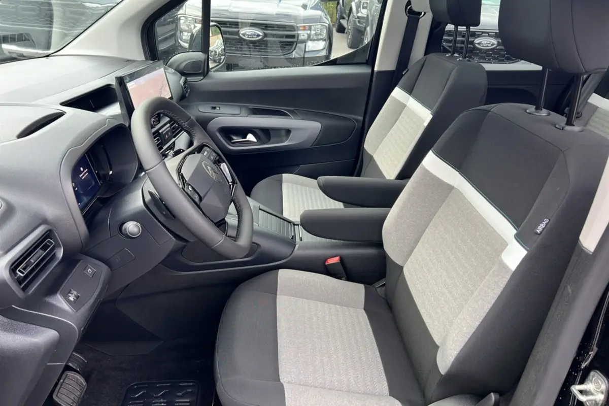 Vue intérieure côté conducteur du Citroën Berlingo 2025 noir perla nera, sièges bicolores et tableau de bord moderne.