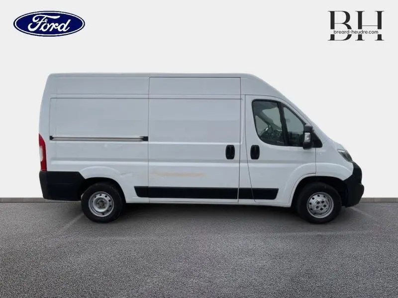 Profil droit d'un utilitaire blanc banquise Citroën Jumper FGN 33 L2H2 avec portes latérales et arrière battantes visibles