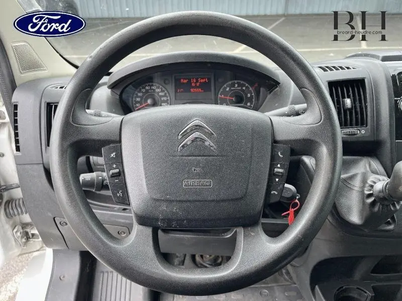 Vue intérieure centrée sur le volant noir du Citroën Jumper blanc, avec tableau de bord et commandes visibles.