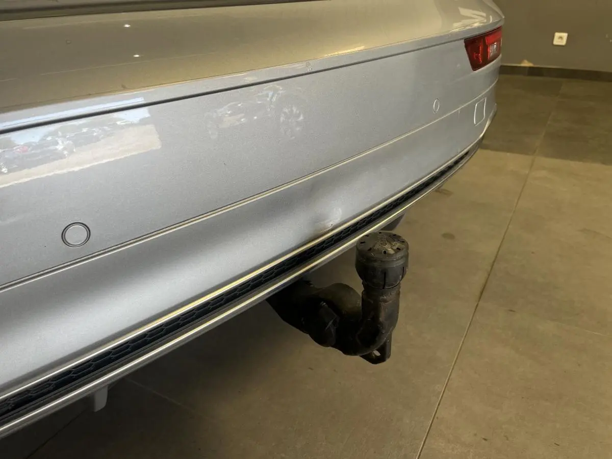 Gros plan sur le pare-chocs arrière gris métallisé de l'Audi Q5 avec crochet d'attelage électrique visible.