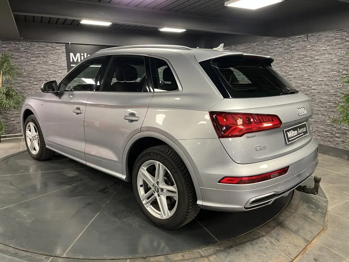 Audi Q5 gris en vue 3/4 arrière droit avec crochet d'attelage et jantes 5 branches doubles.