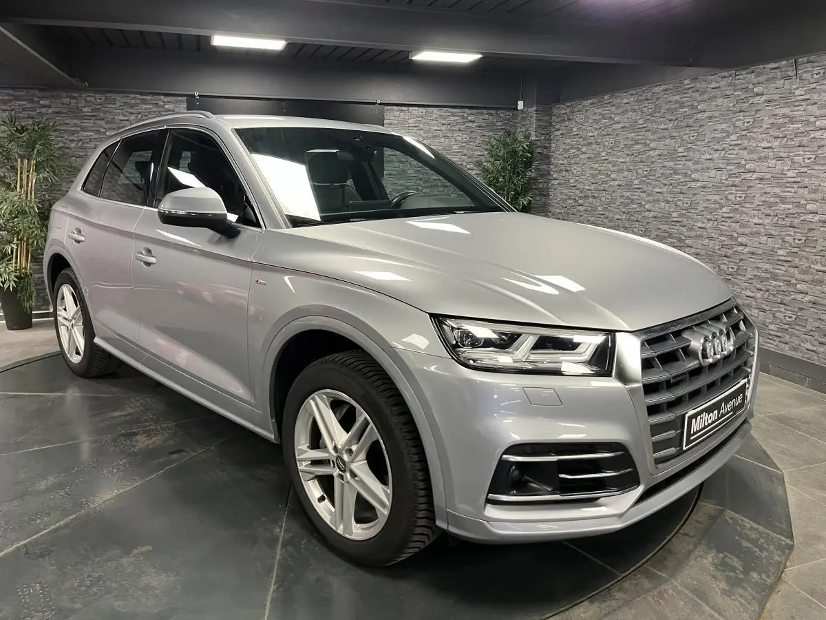 Audi Q5 gris métallisé vue 3/4 avant droit en intérieur avec jantes alliage et calandre distinctive