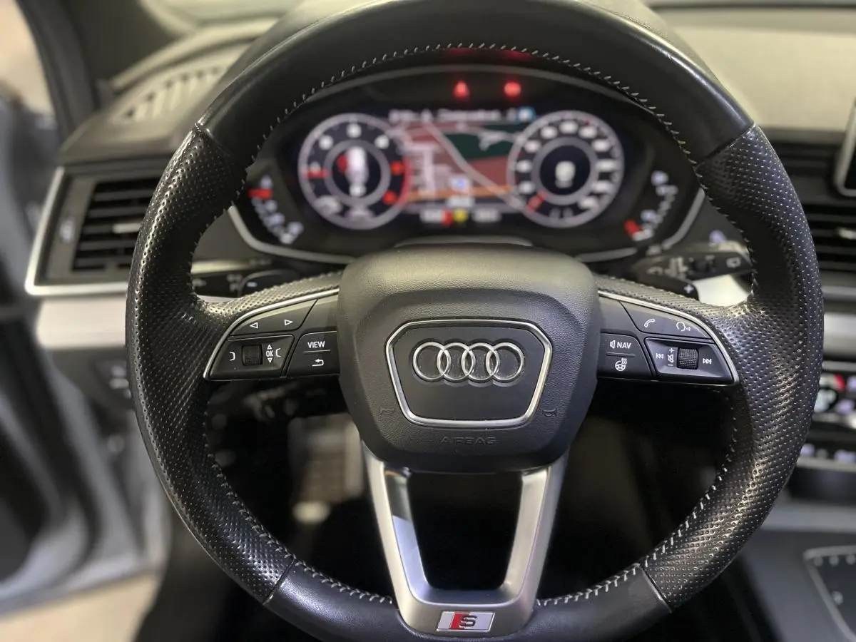 Volant cuir perforé noir S line avec commandes multifonctions et tableau de bord numérique flou en arrière-plan