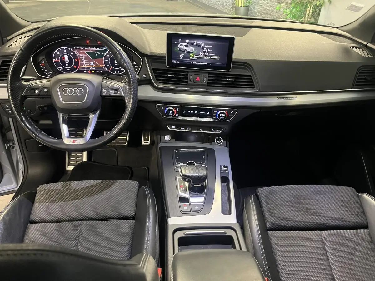 Intérieur Audi Q5 S line 2019 vu de face, volant cuir perforé, écran central et console avec boîte auto gris.