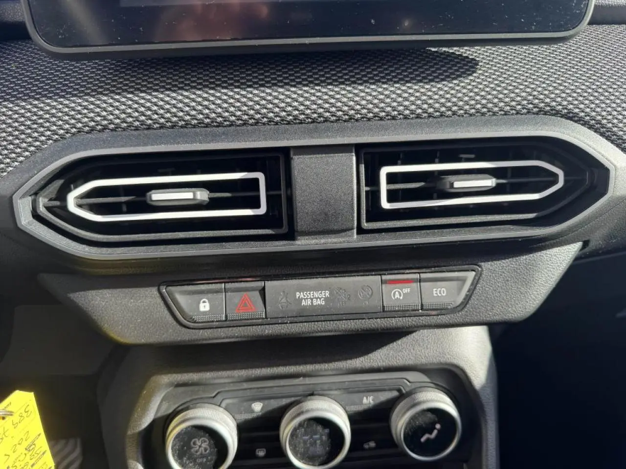 Détail intérieur du tableau de bord du Dacia Jogger gris, montrant les aérateurs centraux et les commandes climatisation.