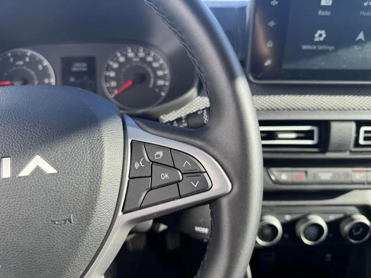 Gros plan sur le volant côté droit du Dacia Jogger gris schiste, avec commandes multifonctions et tableau de bord partiel.