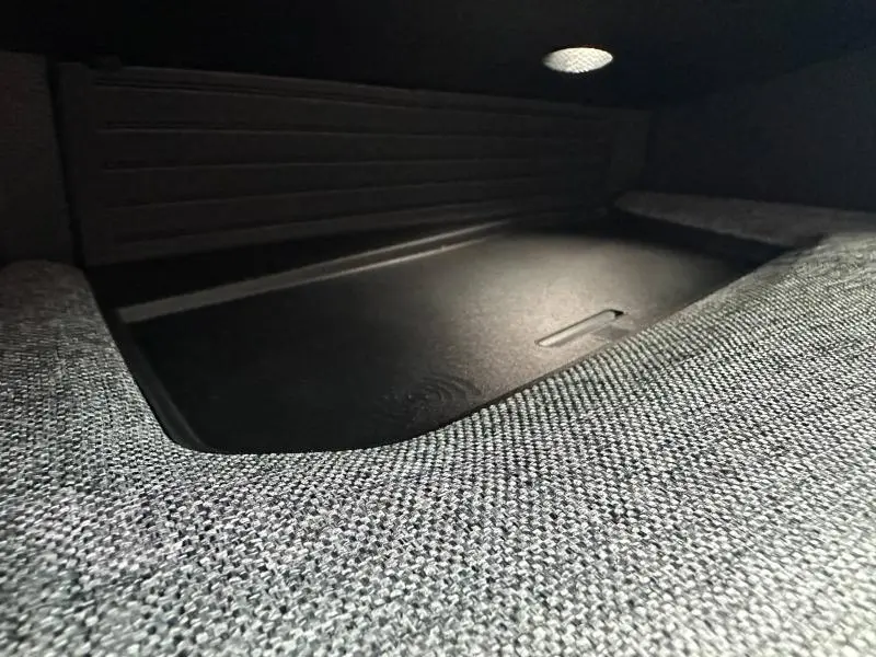 Gros plan sur le tissu gris CRISPY/TEP et le rangement sous l'accoudoir central avant du Peugeot 3008 hybride 2025.