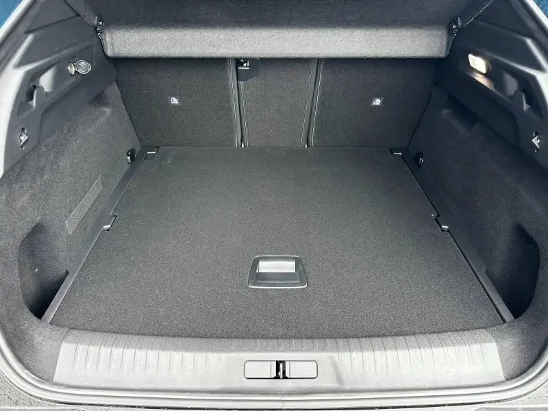 Coffre spacieux du Peugeot 3008 Hybrid 2025 vu de face, revêtement noir et éclairage intérieur actif.