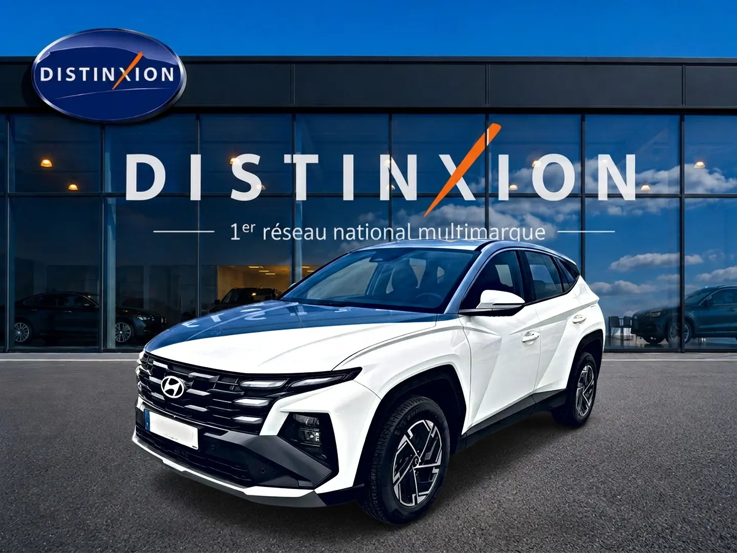 Hyundai Tucson blanc en 3/4 avant droit, avec calandre noire et jantes alliage 17 pouces visibles.