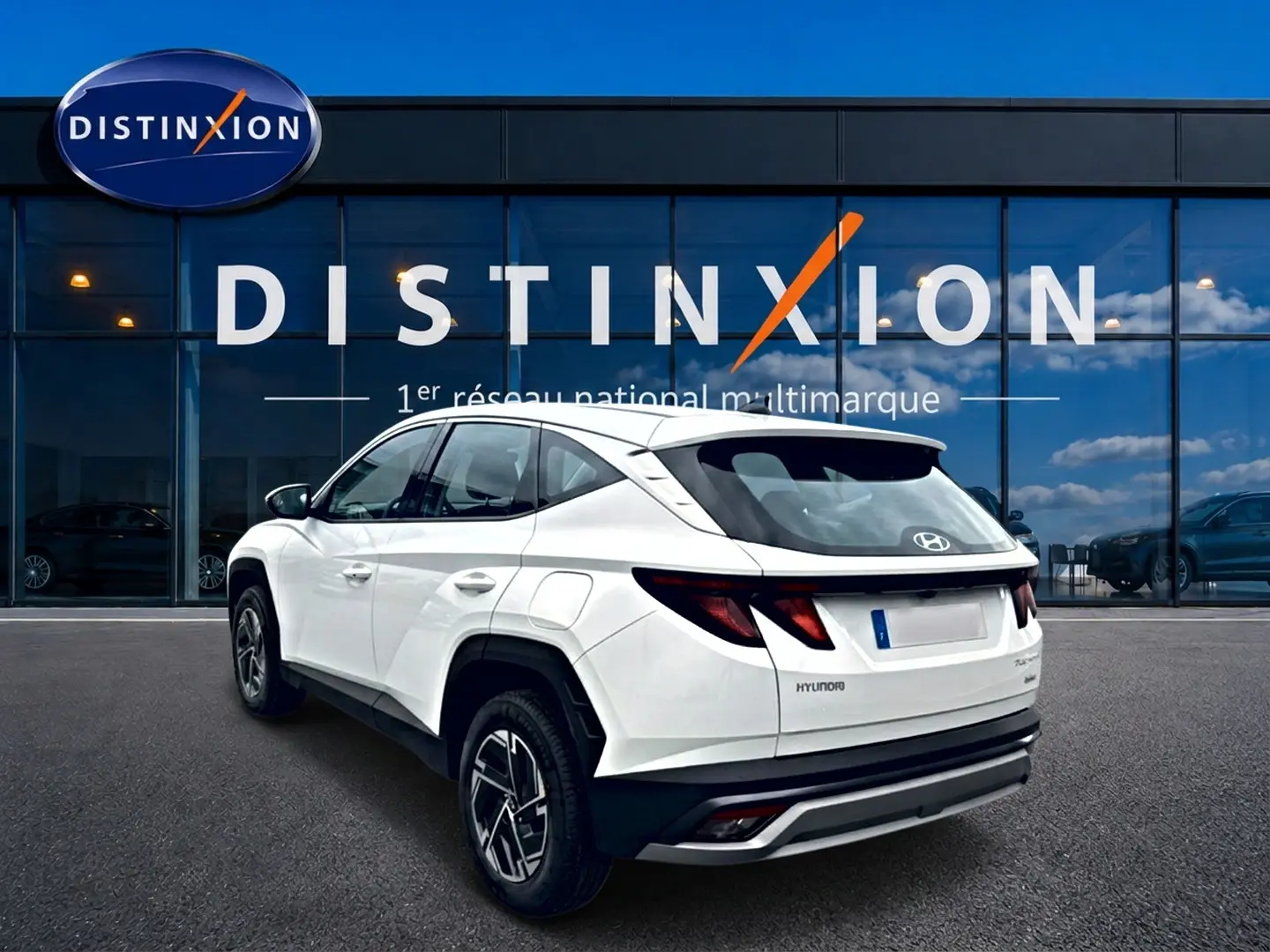 Vue 3/4 arrière droite d'un Hyundai Tucson blanc 2026 hybride avec jantes alliage et feux arrière LED distinctifs.