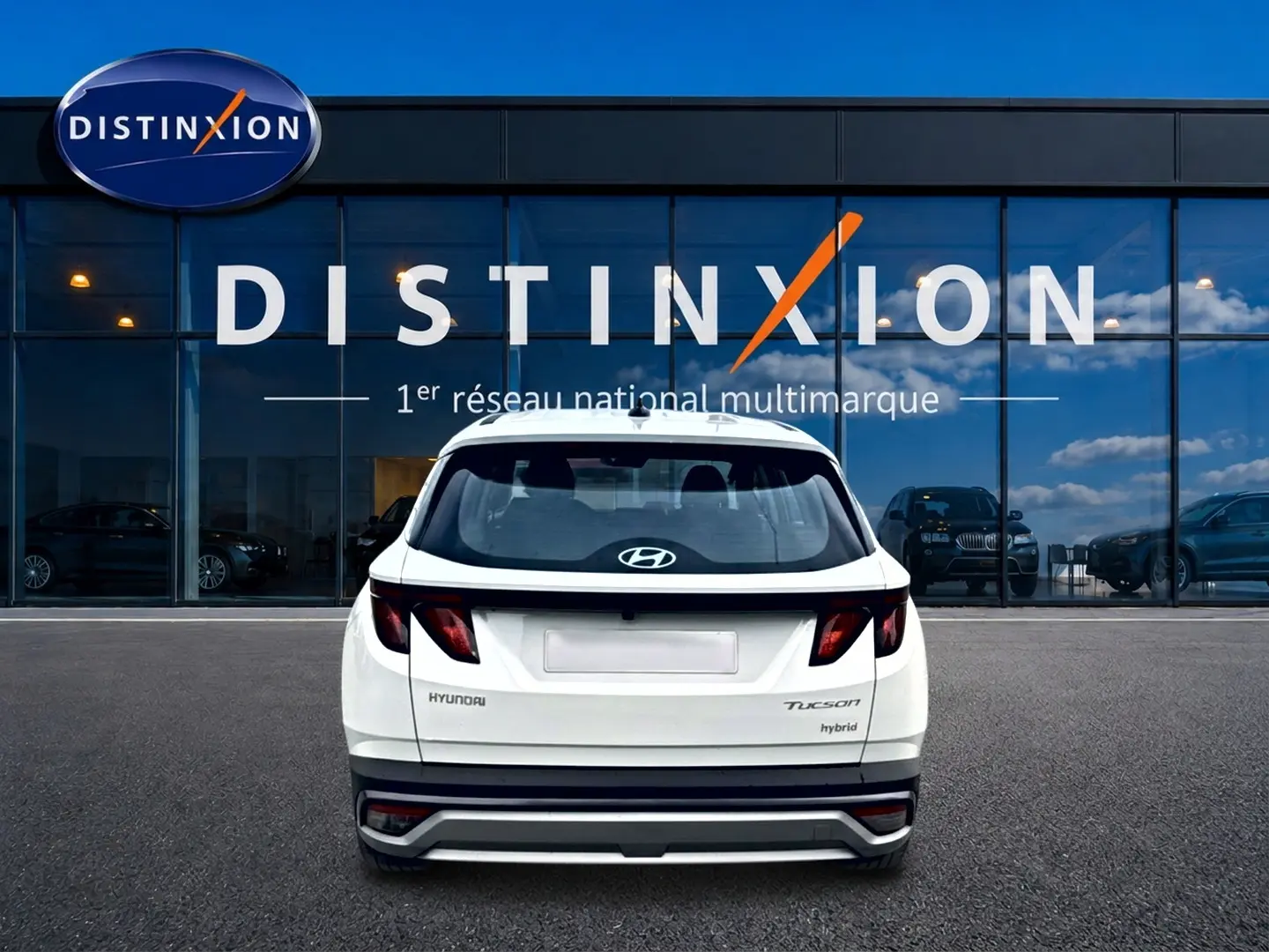 Vue arrière d’un Hyundai Tucson blanc hybride 2026, avec feux arrière sombres et logo Hyundai visible.