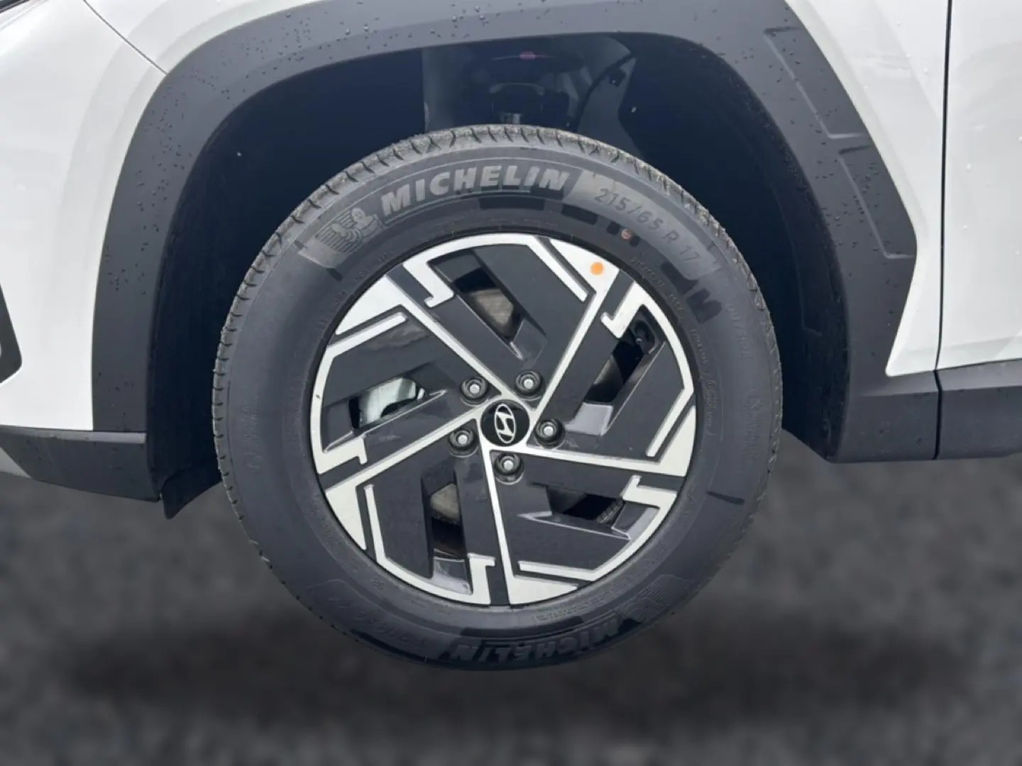 Gros plan sur la roue avant droite blanche d’un Hyundai Tucson 2026 avec jante alliage noire et argentée.