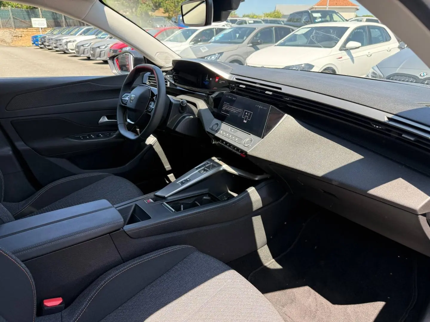 Vue intérieure côté conducteur de la Peugeot e-308 noire, avec tableau de bord digital et écran tactile central.