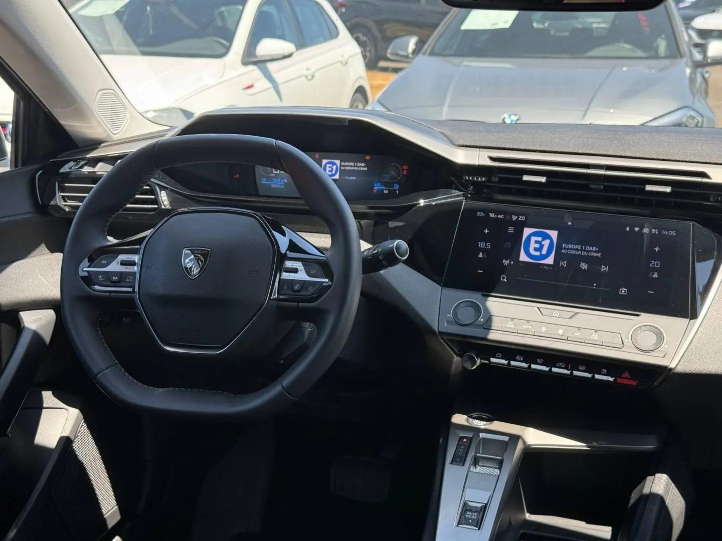 Vue intérieure avant de la Peugeot 308 e-308 noire, volant multifonction et écran tactile central lumineux.