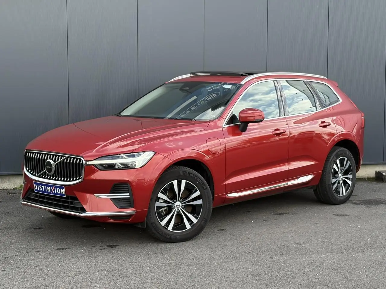 Volvo XC60 T6 AWD PHEV rouge Fusion en 3/4 avant droit avec jantes alliage et toit ouvrant panoramique.