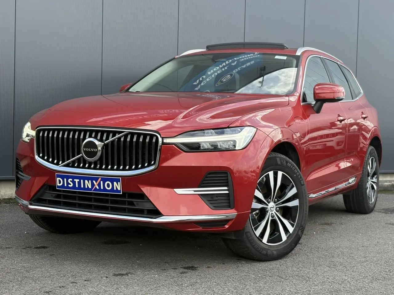 Vue 3/4 avant du Volvo XC60 T6 AWD PHEV rouge Fusion avec calandre chromée et jantes alliage 18 pouces.