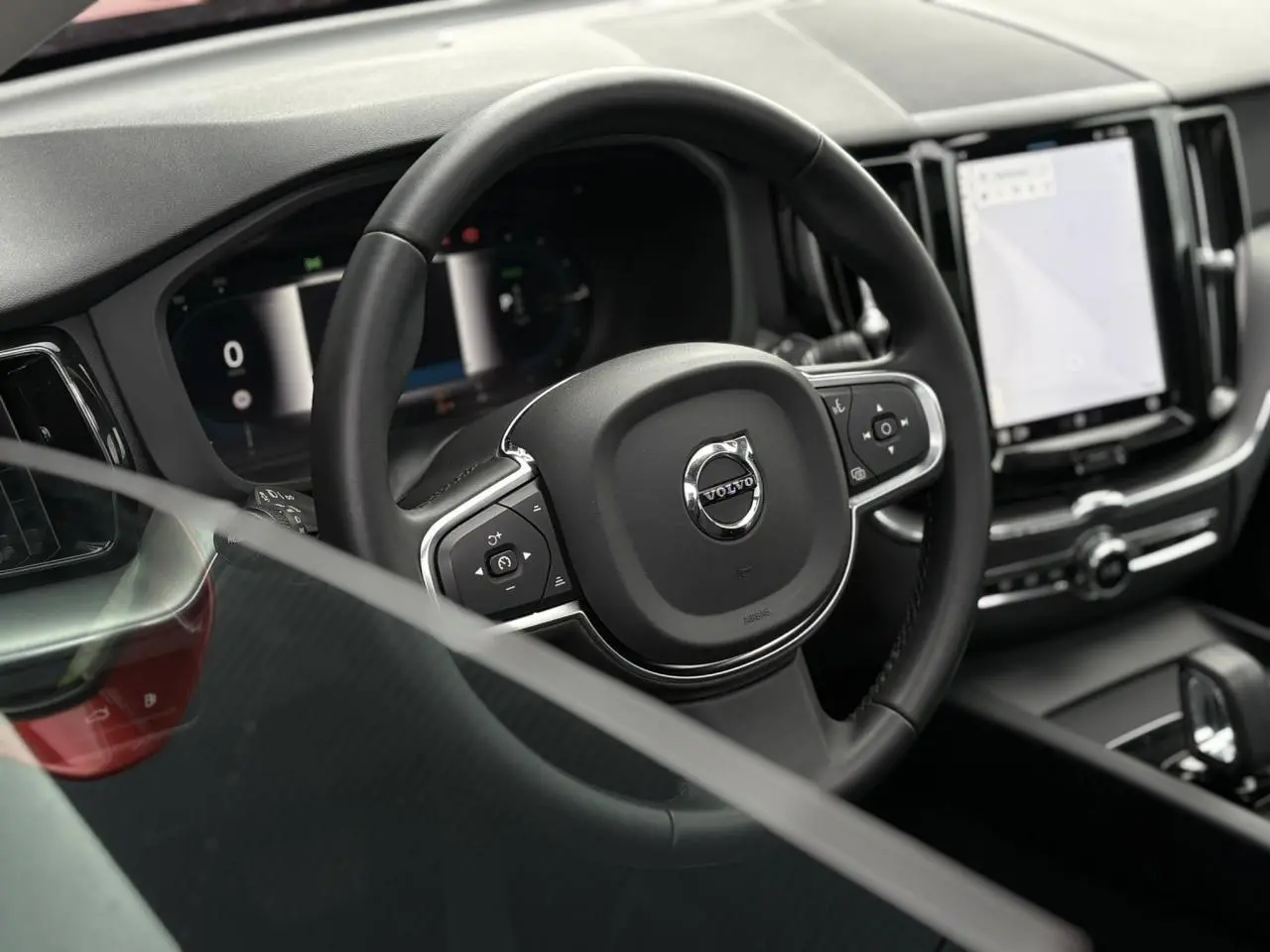 Vue rapprochée du volant noir multifonction et du tableau de bord digital du Volvo XC60 T6 AWD PHEV 2024.