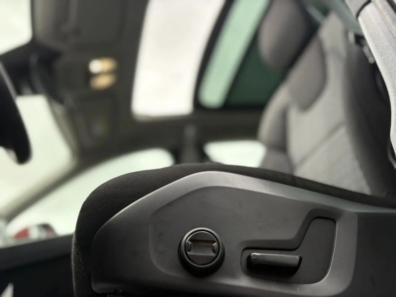 Gros plan sur les commandes électriques du siège avant d'un Volvo XC60 rouge Fusion 2024 avec toit ouvrant panoramique.