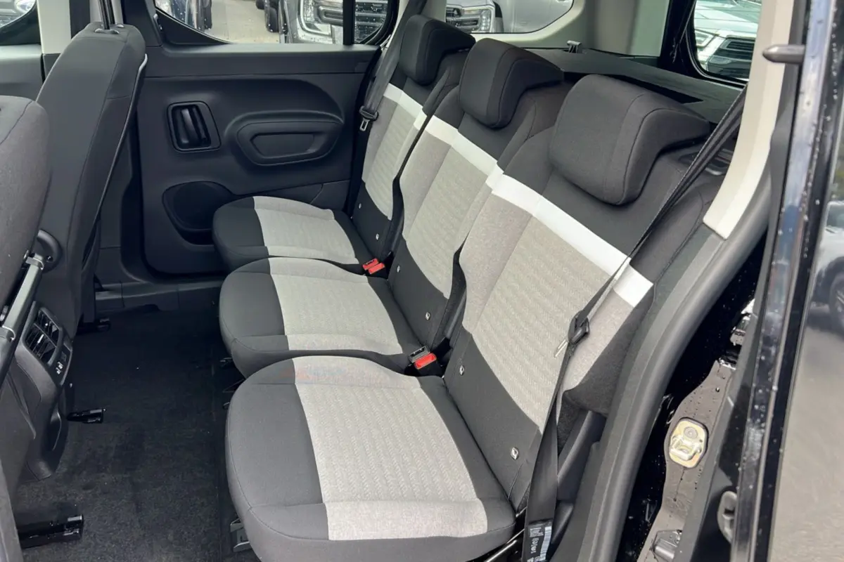 Vue intérieure côté droit du Citroën Berlingo 2025 noir perla nera, montrant la banquette arrière trois places en tissu bicolore.