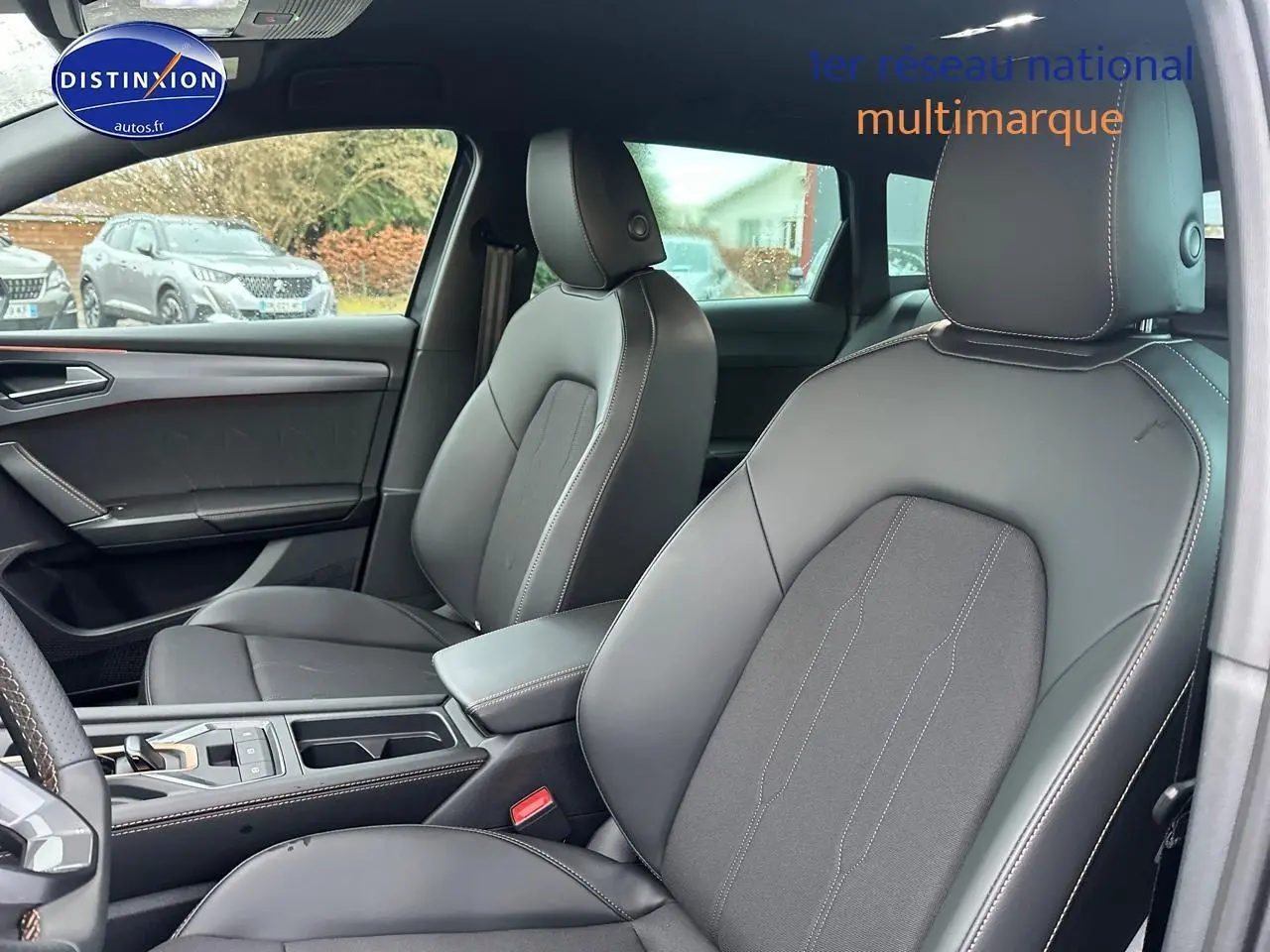 Vue intérieure avant de la CUPRA LEON ST 1.5 etsi hybrid 2025 avec sièges cuir gris et accoudoir central.