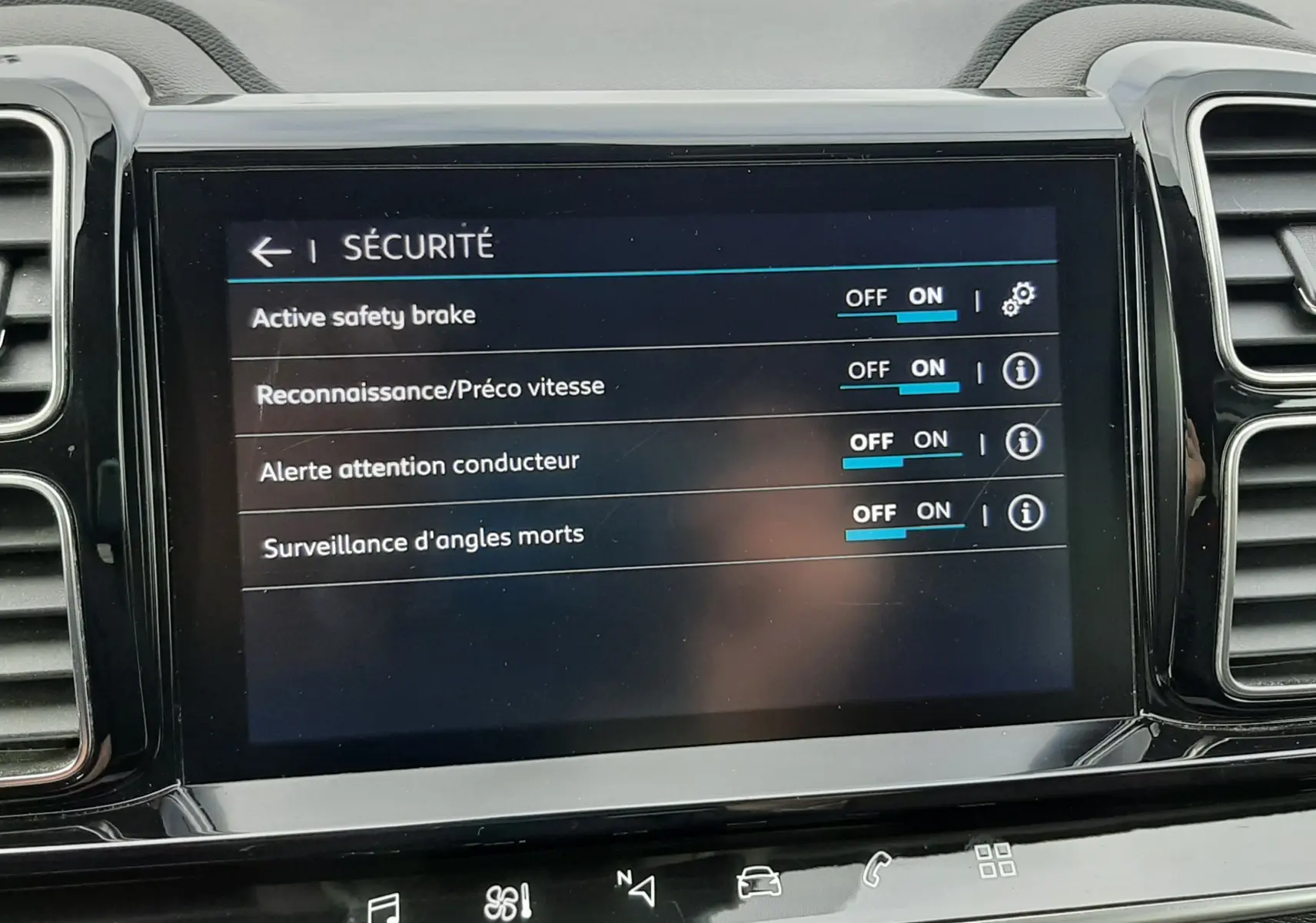 Vue rapprochée de l'écran tactile central du Citroën C5 Aircross blanc, affichant le menu sécurité avec options activées.