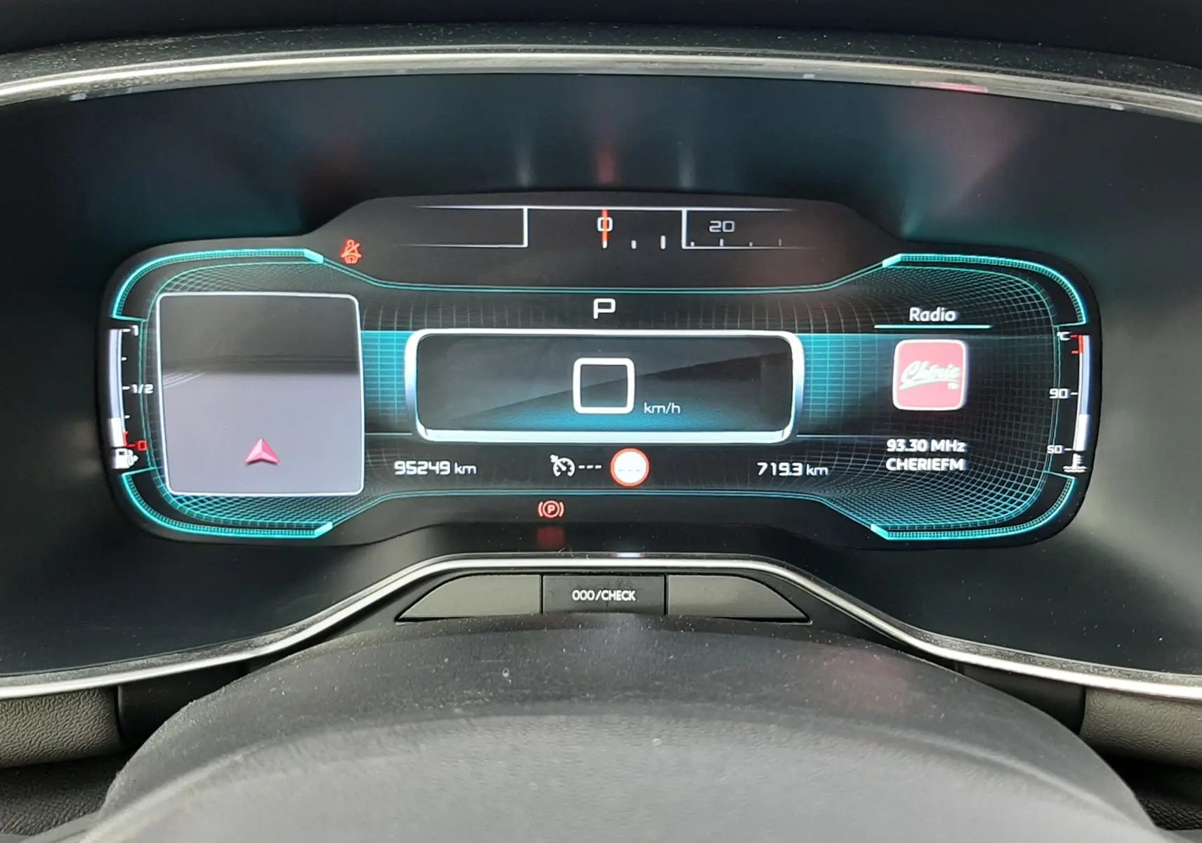 Vue rapprochée du tableau de bord numérique du Citroën C5 Aircross blanc, affichant la vitesse et la radio.